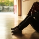 Young man sitting on floor looking dejected.