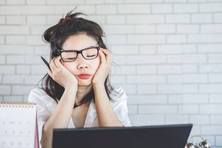 Woman in front of computer looking tired and not getting work done.