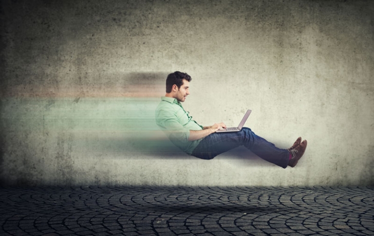 Man with laptop rushing by in an office.