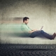 Man with laptop rushing by in an office.