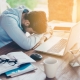 Man sleeping at his desk with laptop and papers around.